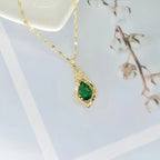 Halsband med grön sten i bladhänge i två designer i guldfärg