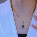 Halsband med grön sten i bladhänge i två designer i guldfärg