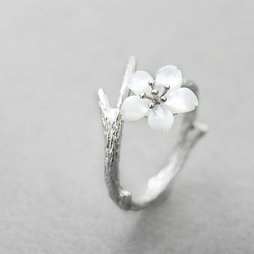 Justerbar ring med vit blomma på grenformad skena