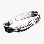 Pulsera trenzada en tono plateado con detalle tejido en la muñeca